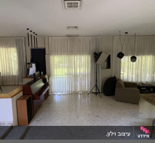וילונות לבנים תלויים על חלונות גדולים בסלון